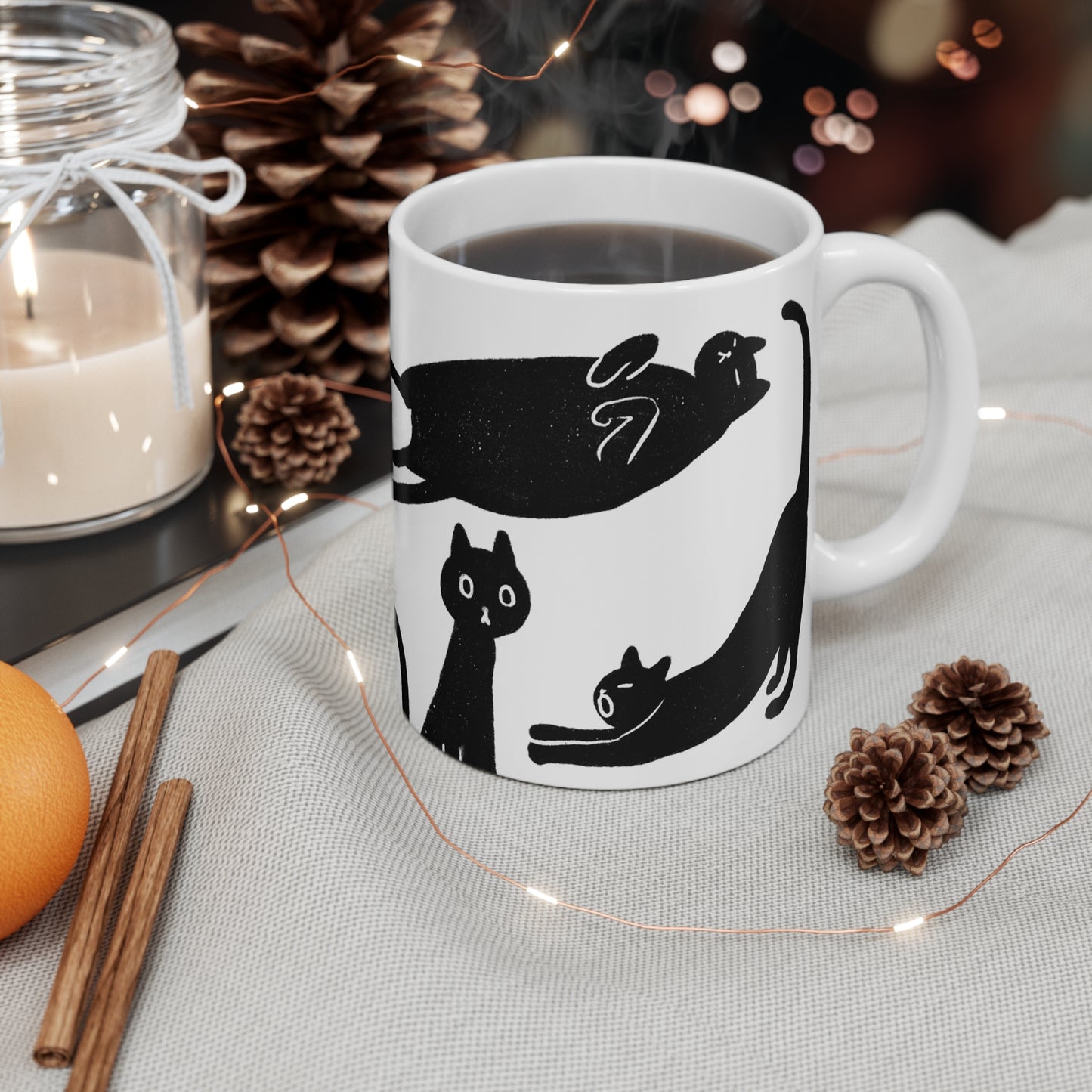 Black and white ceramic mug featuring illustrated black cats in various playful poses.
