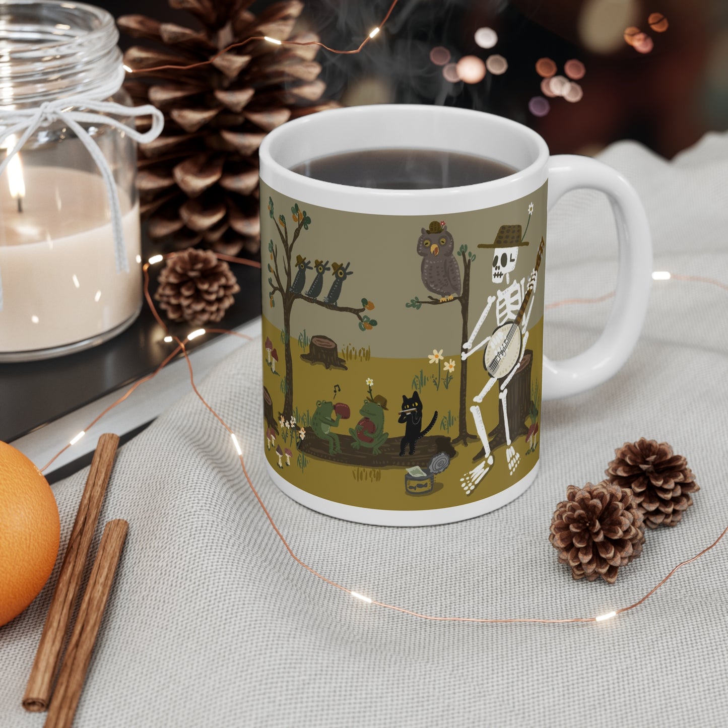 Illustrated ceramic mug with skeleton playing banjo, frogs, cat, and owls in a forest band scene