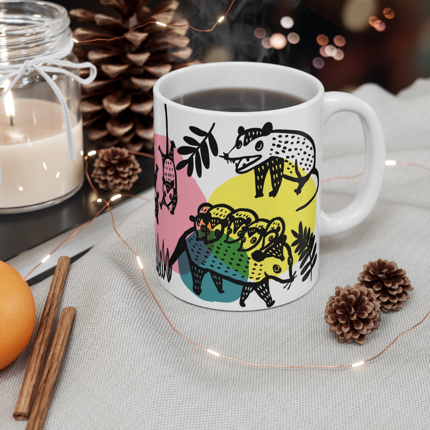 White ceramic mug with illustrated opossums, surrounded by colorful abstract shapes