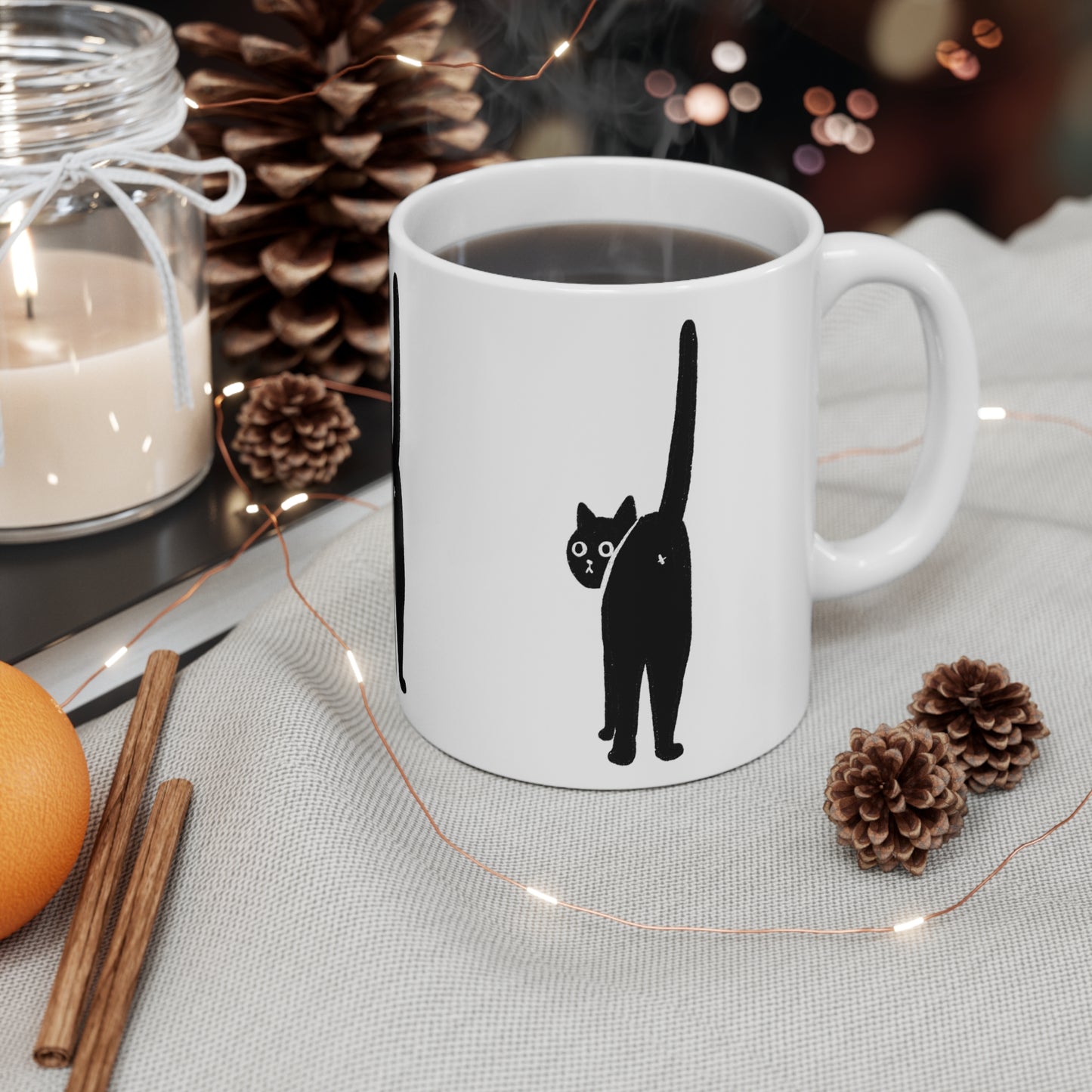 White ceramic mug with a minimalist black cat illustration facing backward with its tail raised.