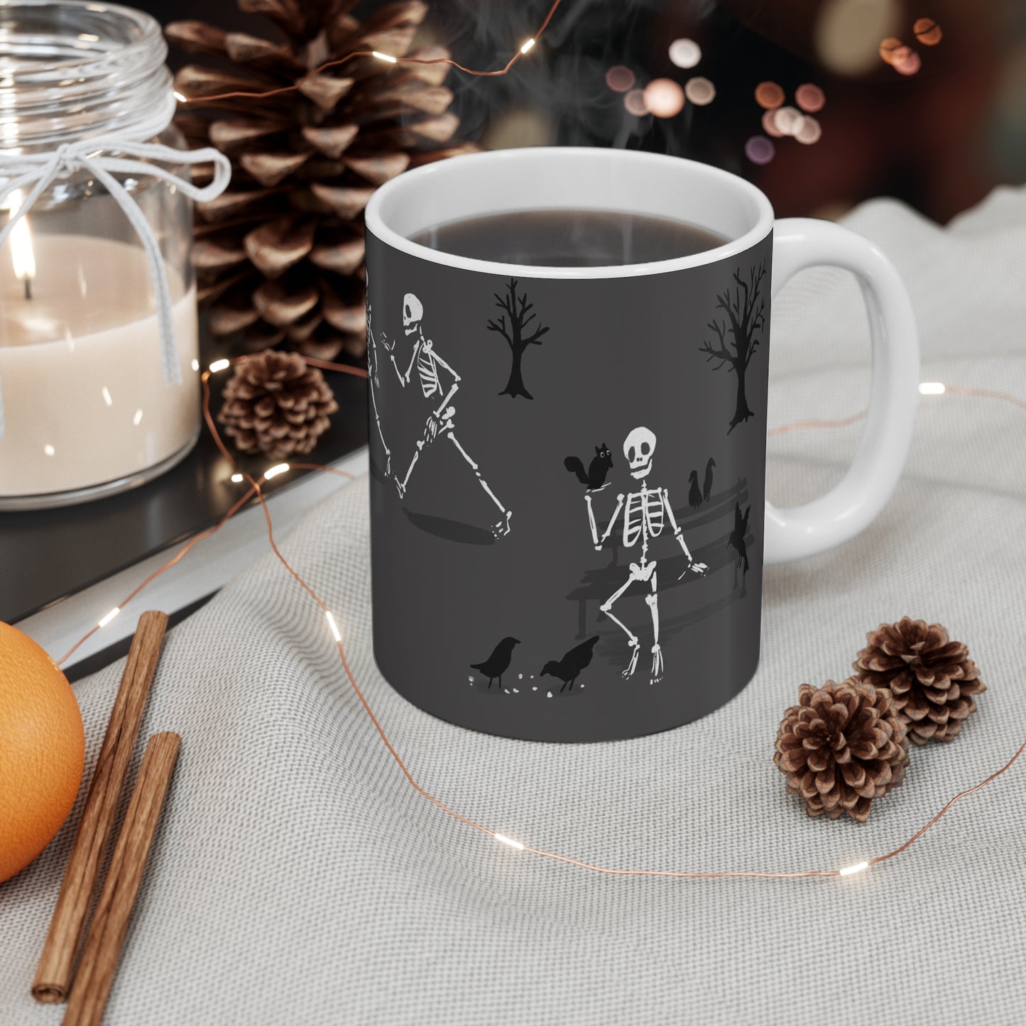 Ceramic mug featuring skeletons walking through a park and feeding birds in a whimsical autumn illustration.