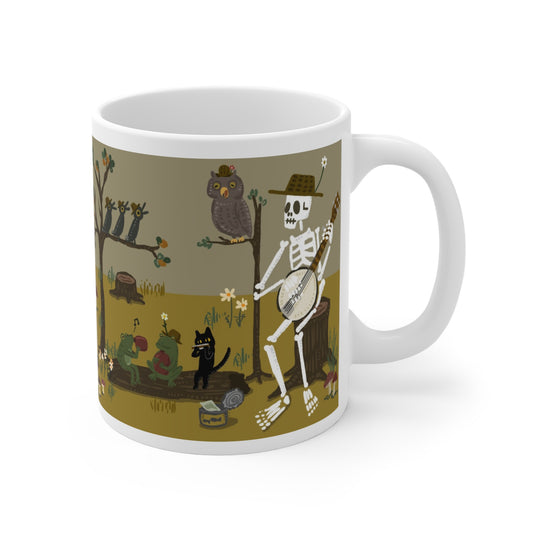Illustrated ceramic mug with skeleton playing banjo, frogs, cat, and owls in a forest band scene
