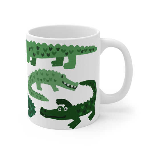 White ceramic mug featuring illustrated green alligators with heart-shaped patterns