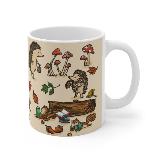 Ceramic mug featuring a whimsical woodland tea party with a fox, rabbit, squirrels, and hedgehogs surrounded by mushrooms, leaves, and books.