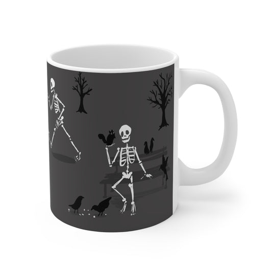 Ceramic mug featuring skeletons walking through a park and feeding birds in a whimsical autumn illustration.