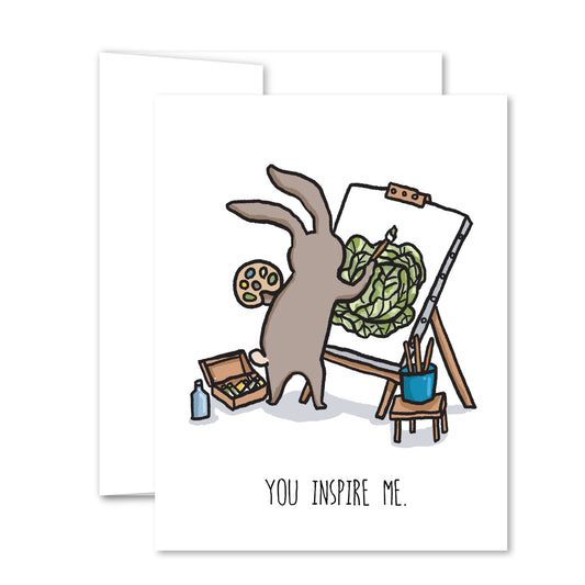 Whimsical encouragement card with a hand-drawn rabbit artist painting a cabbage at an easel and the message “You Inspire Me.”