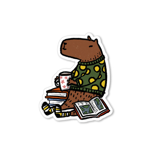 Illustrated capybara cozy sticker wearing sweater, sipping mug, with books, warm animal art by Miss Johnny Squirrel.
