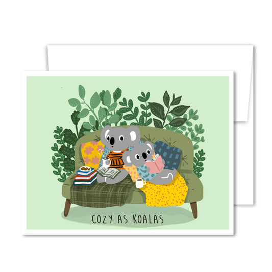Illustrated koalas reading on a couch with tea and cookies, “Cozy As Koalas” friendship greeting card surrounded by plants