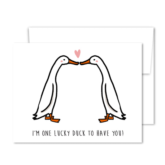 Illustrated two white ducks touching beaks with a pink heart above, “One Lucky Duck to Have You” love greeting card