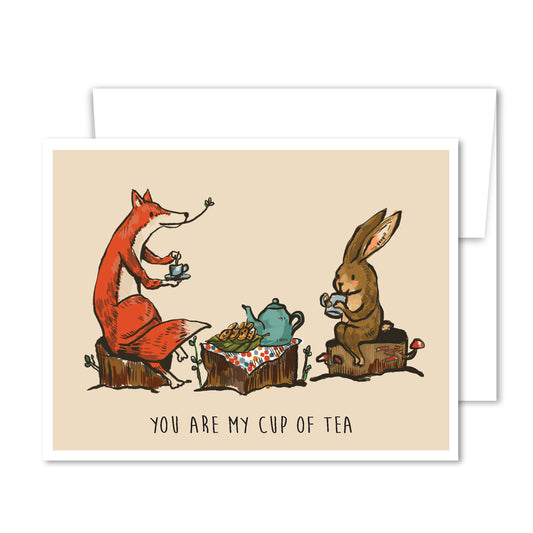 Whimsical greeting card with a fox and rabbit sharing tea at a woodland table, illustrated in warm earthy tones.